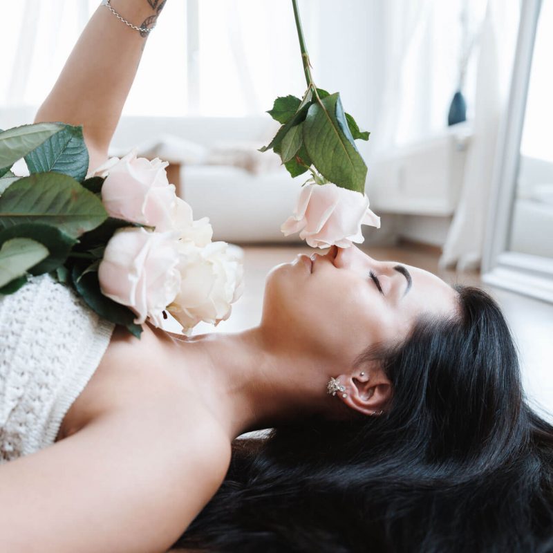 Florales Fotoshooting von Rose & Co mit einem Model, das an einer Rose riecht und die Sinnlichkeit und Natürlichkeit der floralen Gestaltung betont