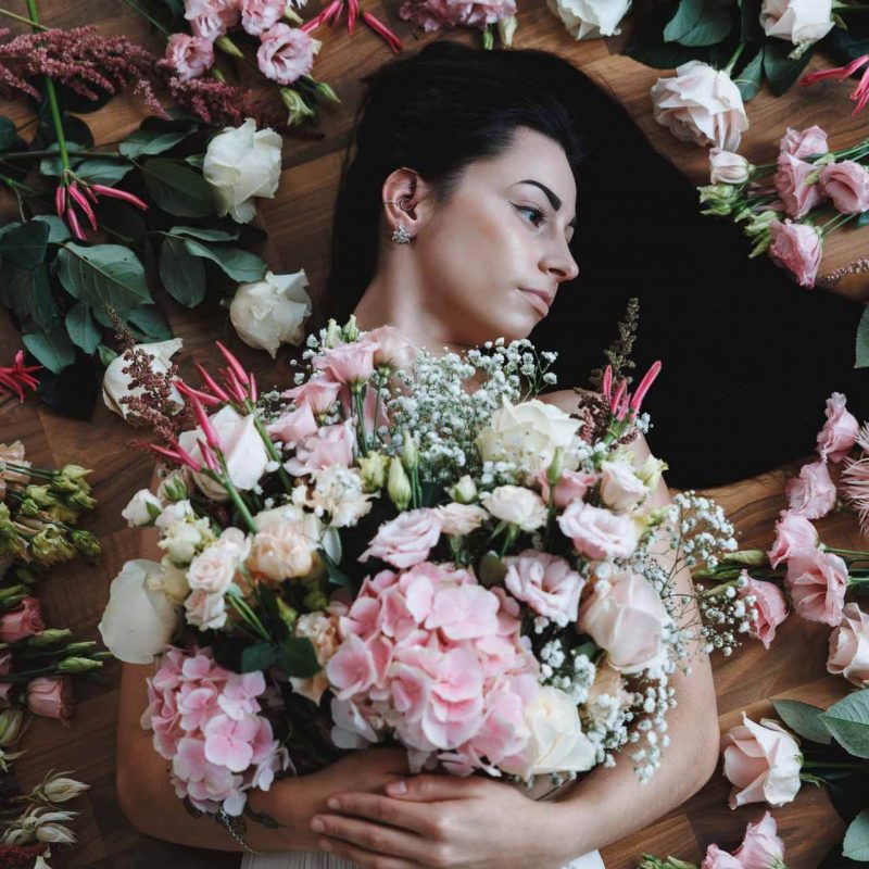 Model umgeben von floralen Elementen aus dem Fotoshooting von Rose & Co