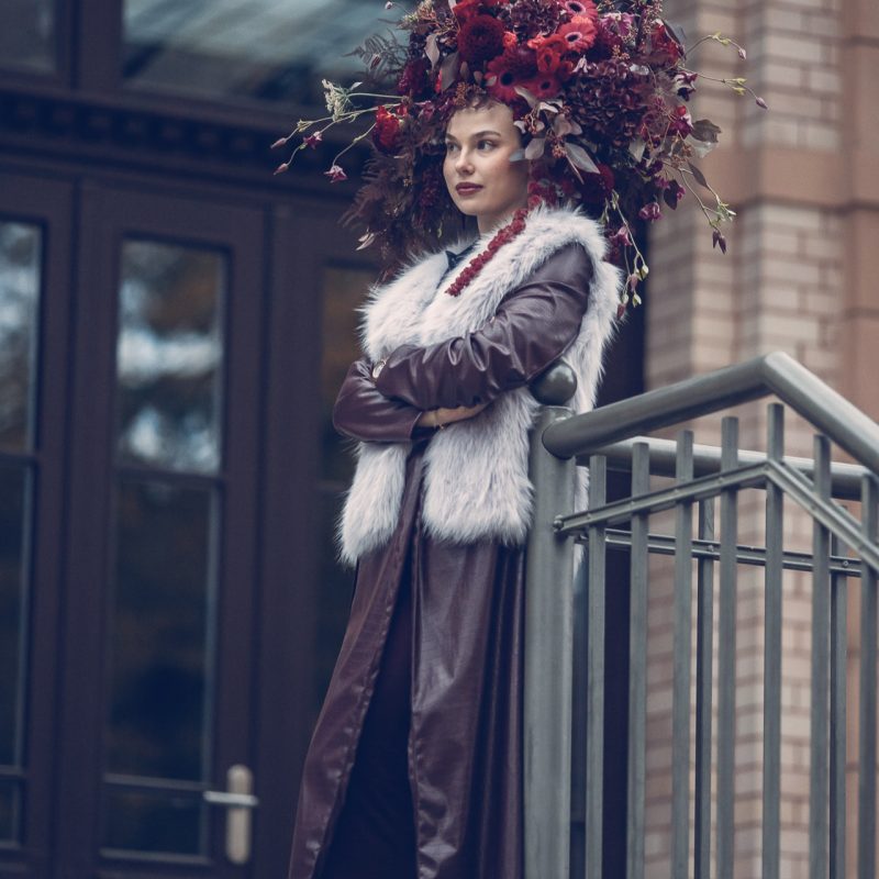 Model trägt eine großflächige florale Blumenpracht auf dem Kopf, gestaltet von Rose & Co