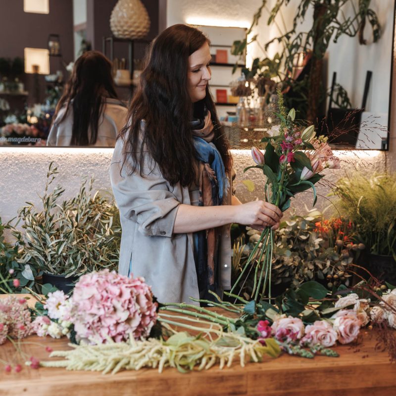 Sophie Ziegler bei Rose & Co am Tresen, umgeben von Blumen und Arbeitsmaterialien, als authentischer Einblick in den Floristikalltag